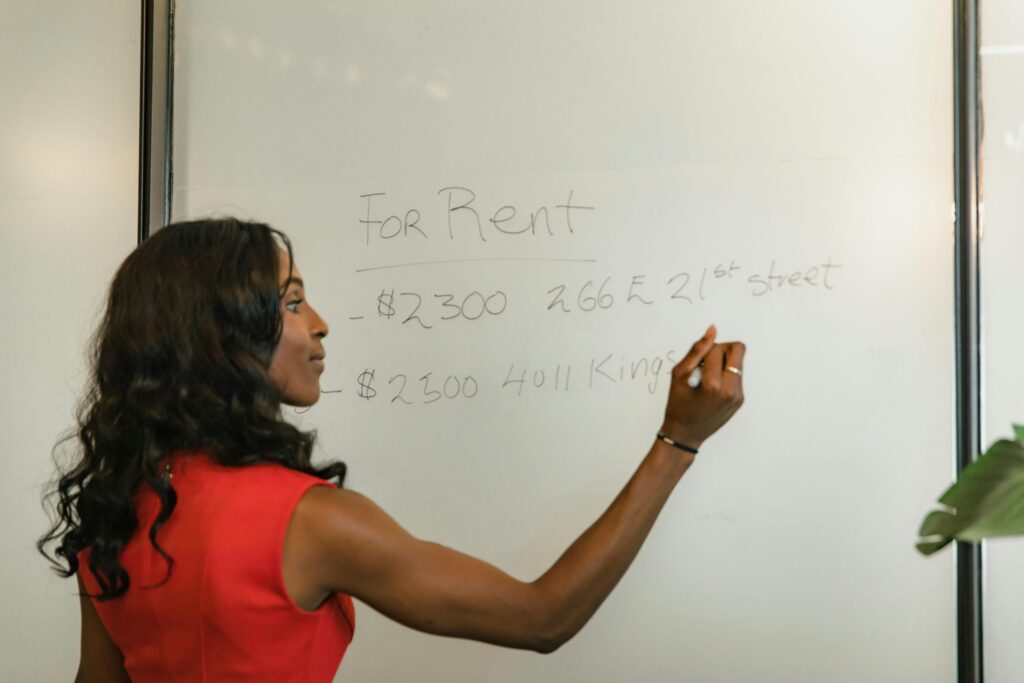 pexels photo 10376001 10376001 Professional woman writing real estate prices on a whiteboard for rental properties.