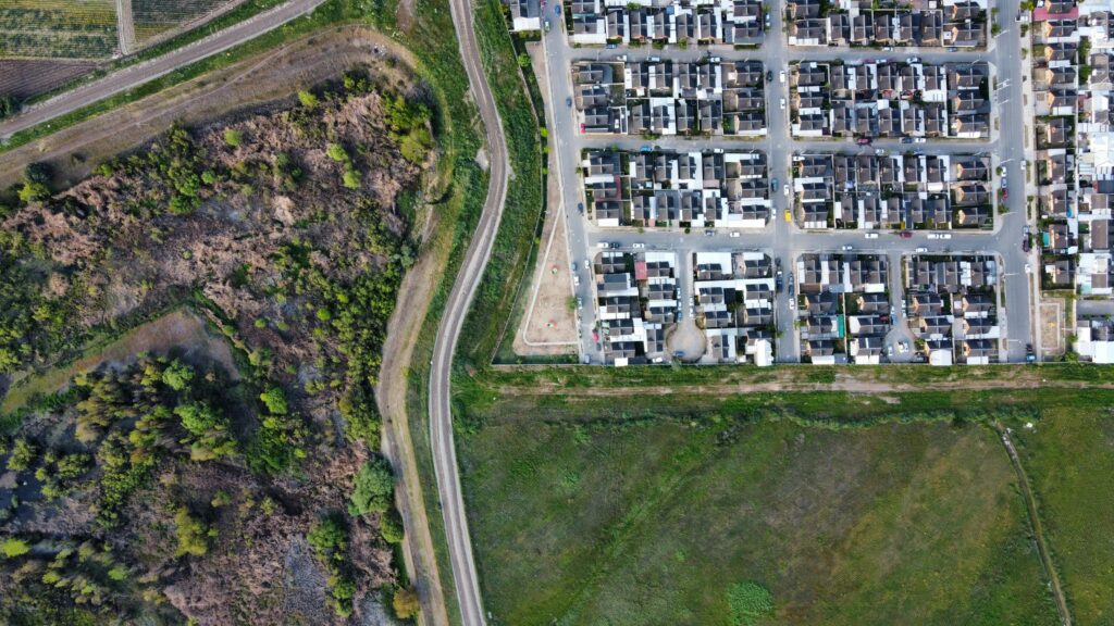 pexels photo 11201060 11201060 Drone view of a residential neighborhood alongside a natural landscape, showcasing urban and rural contrast.