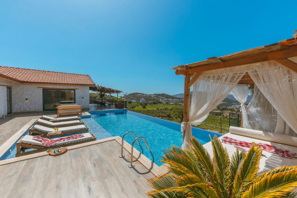 pexels photo 20975735 20975735 Elegant villa with an infinity pool, deckchairs, and cabana offering a panoramic hillside view.