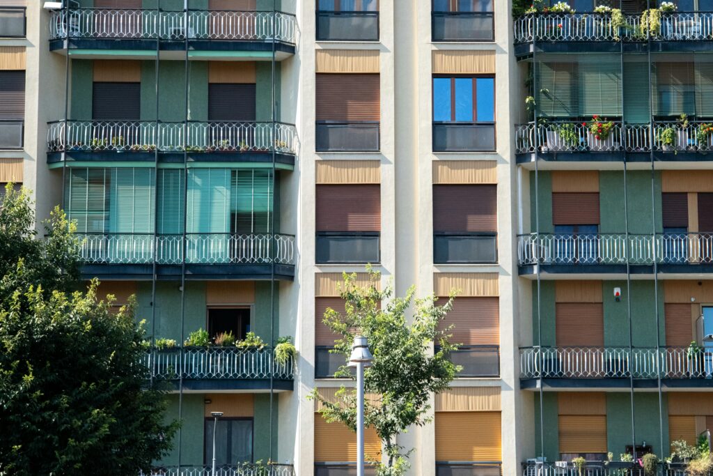 pexels photo 27451770 27451770 Contemporary apartment facade with glass balconies and green accents, capturing urban residential life.