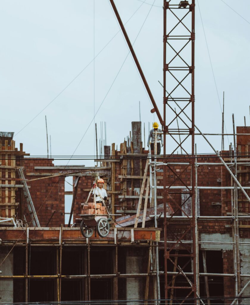 pexels photo 33011845 33011845 A construction worker on a scaffold at a building site with cranes and brickwork visible.