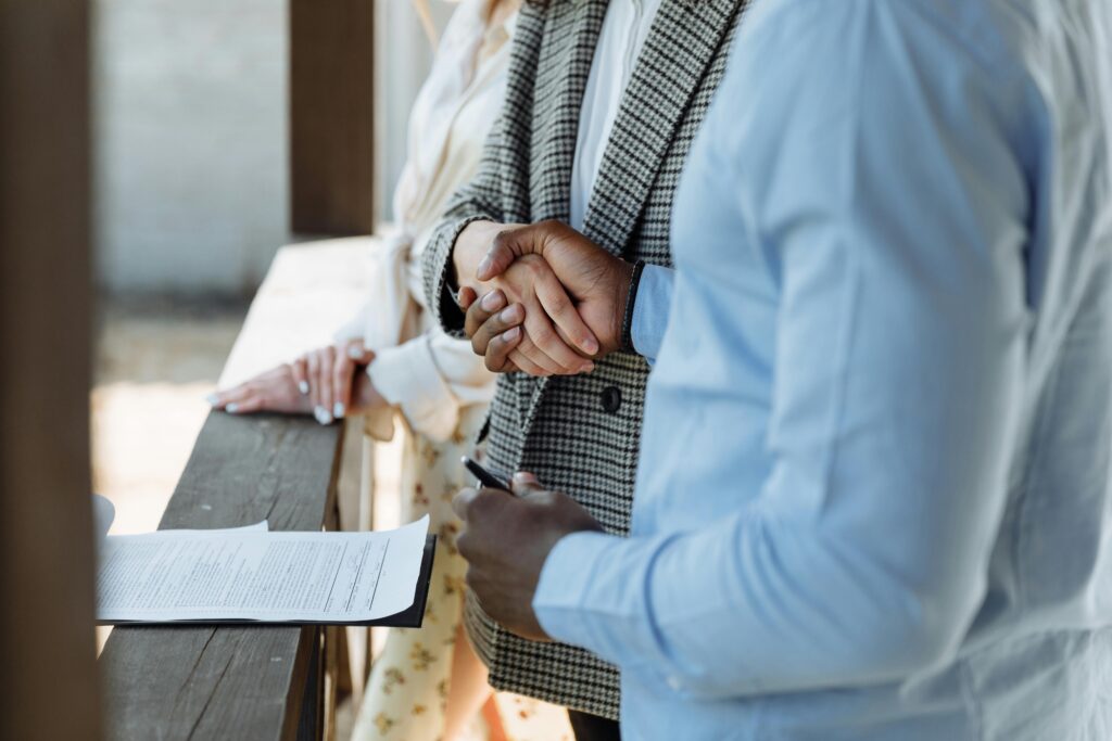 pexels photo 8470844 8470844 A close-up of hands shaking over a signed property agreement, symbolizing a successful real estate deal.